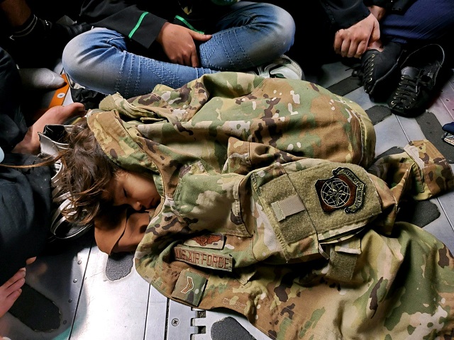 An Afghan girl lays on the floor of a C-17 Globemaster III near Kabul, Afghanistan. The blouse covering the girl belonged to U.S. Air Force Airman 1st Class Nicolas Baron, 305th Air Mobility Wing loadmaster, who was a member of the crew that airlifted refugees to safety. (Courtesy photo by U.S. Air Force Capt. Mark Lawson)